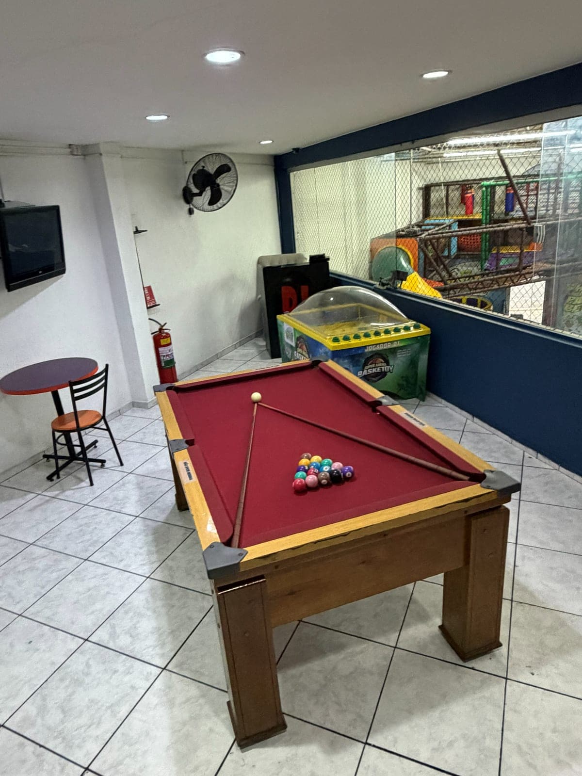 Mesa de sinuca com vista para o brinquedão através do vidro